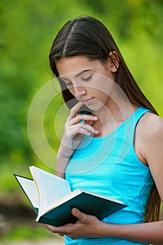 Beautiful teenage girl reading book