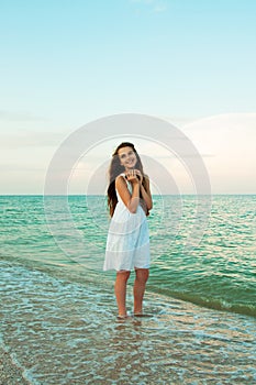 Beautiful teenage girl with the shell on the evening beach