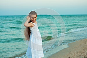 Beautiful teenage girl with the shell on the evening beach.