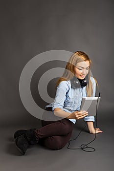 Beautiful teenage girl sitting on the floor with headphone and h
