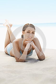 Beautiful Teenage Girl Smiling While Lying On Sandy Beach