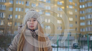 Beautiful teenage girl in warm clothes walking and talking outdoors at winter day