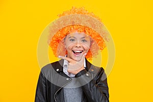 Beautiful teenage girl in wig isolated on yellow. Funny clown wig. Happy girl face, positive and smiling emotions.