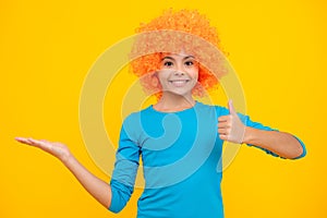 Beautiful teenage girl in wig isolated on yellow. Funny clown wig. Happy teenager portrait. Smiling girl.