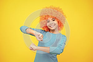 Beautiful teenage girl in wig isolated on yellow. Funny clown wig. Happy teenager portrait. Smiling girl.
