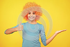 Beautiful teenage girl in wig  on yellow. Funny clown wig. Happy teenager portrait. Smiling girl.