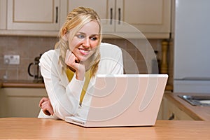 Beautiful Teenage Girl Young Woman Using Laptop Computer in her Kitchen