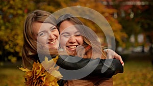 Beautiful Teenage Girls Having Fun in Autumn Park . Two Young Laughing Girls Hugging in the Autumn Park and Holding a