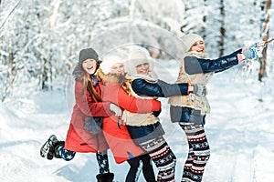 Beautiful teenage girls having fun outside in a wood with snow in winter. Friendship and active life consept