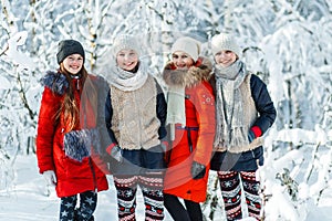 Beautiful teenage girls having fun outside in a wood with snow in winter. Friendship and active life consept