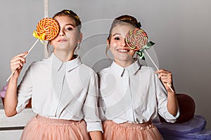 Beautiful teenage girls in pink tutu skirts with lollipops and macaroons and fansy cakes in studio on white background