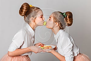 Beautiful teenage girls in pink tutu skirts with lollipops and macaroons and fansy cakes in studio on white background