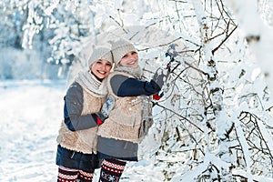 Beautiful teenage girls twins sisters having fun outside in a wood with snow in winter. Friendship, family, consept