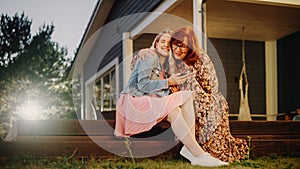 Beautiful Teenage Granddaughter Hugging with Her Grandmother While Using a Smartphone. Girl Showing