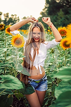 Beautiful Teenage Model girl with long healthy hair posing on the Sunflower Spring Field