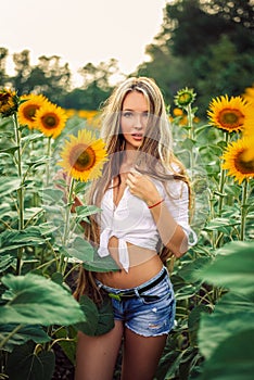 Beautiful Teenage Model girl with long healthy hair posing on the Sunflower Spring Field