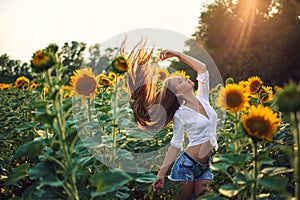 Beautiful Teenage Model girl with long healthy hair posing on the Sunflower Spring Field