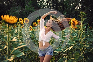 Beautiful Teenage Model girl with long healthy hair posing on the Sunflower Spring Field