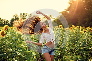 Beautiful Teenage Model girl with long healthy hair posing on the Sunflower Spring Field