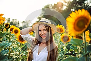 Beautiful Teenage Model girl with long healthy hair posing on the Sunflower Spring Field