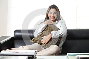 Beautiful teenager on a couch at home embracing a cushion