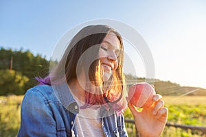 Beautiful teenager girl with red apple, happy young woman on nature