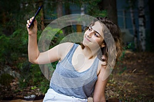 Beautiful teenager girl taking a selfie at the forest. Using technology