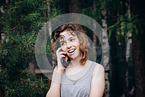 Beautiful teenager girl talking by phone at the forest. Using technology