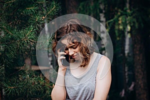 Beautiful teenager girl talking by phone at the forest. Using technology