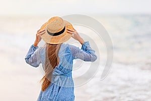 Beautiful teenager girl on tropical seashore at sunset. Beautiful little girl in dress at beach look at the sea.