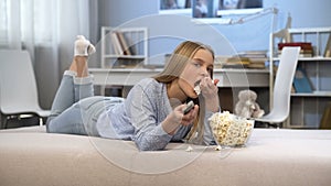 Beautiful teenager girl watching tv and eating pop corn, entertainment time