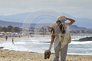 Beautiful teenager goes on the beach. The girl with her long hair is walking on the beach in Greece.