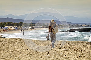 Beautiful teenager goes on the beach. The girl with her long hair is walking on the beach in Greece.