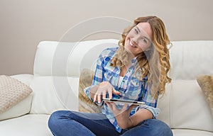 Beautiful teenager using tablet pc sitting on sofa