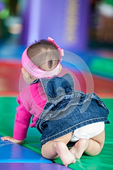 Beautiful ten months baby girl crawling on a colorful background. Early stimulation for toddlers concept