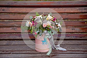 Beautiful tender bouquet of flowers in pink box on wooden background