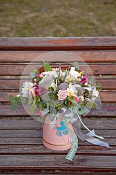 Beautiful tender bouquet of flowers in pink box on wooden background