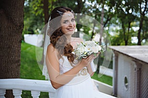 A beautiful tender bride is holding her wedding bouquet and smiling happily.Wedding image, wedding style concept.