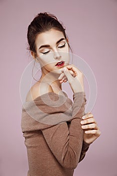 Beautiful tender girl posing in profile with closed eyes over pink background.