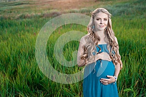 Beautiful tender pregnant woman standing on green grass