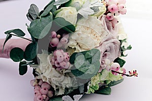 Beautiful tender wedding bouquet of cream roses and eustoma flowers lies on the table, soft focus