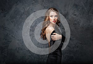 Beautiful tender young woman in black dress with open back