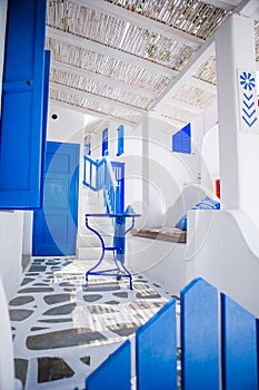 Beautiful terrace with blue chair and table, stairs and flowers. Beautiful terrace exterior with cycladic style.