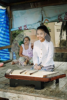 A beautiful Thai girl playing Khim, the traditional Thai music Instrument near the grandmother