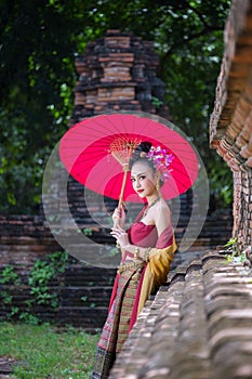 Beautiful Thai girl in traditional dress costume red umbrella as