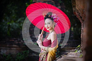 Beautiful Thai girl in traditional dress costume red umbrella as