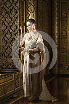 Beautiful Thai girl in traditional Thai national costume Standing by the window of a beautiful golden Thai house