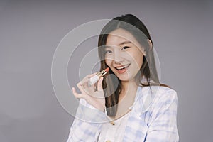 Beautiful thai woman with lipstick isolated over grey background
