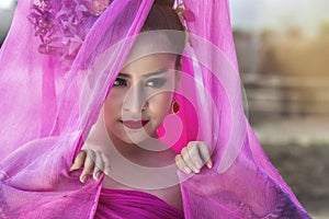 Beautiful Thai woman wearing traditional Thai dress with silk fabric cover her head