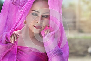 Beautiful Thai woman wearing traditional Thai dress with silk fabric cover her head